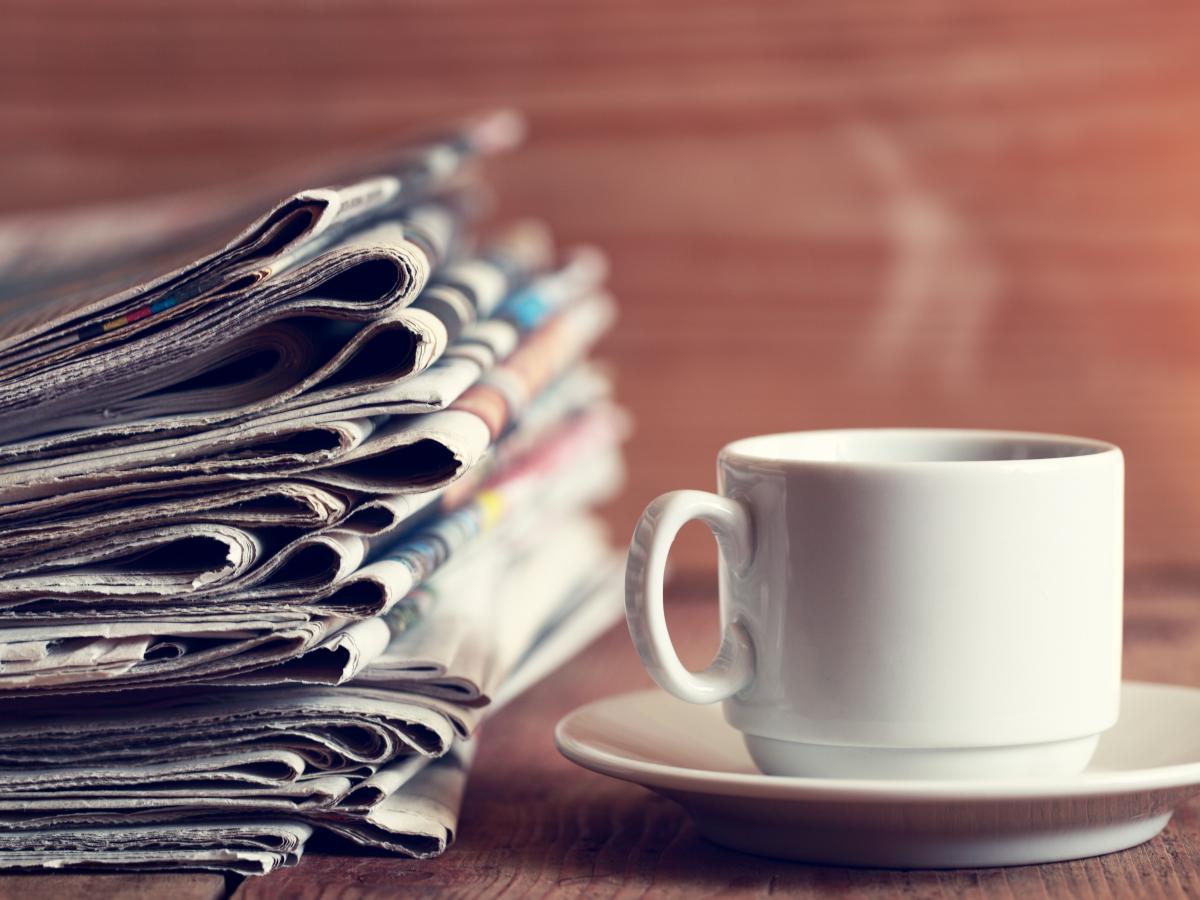 Stack of newspapers and a cup of hot coffee.