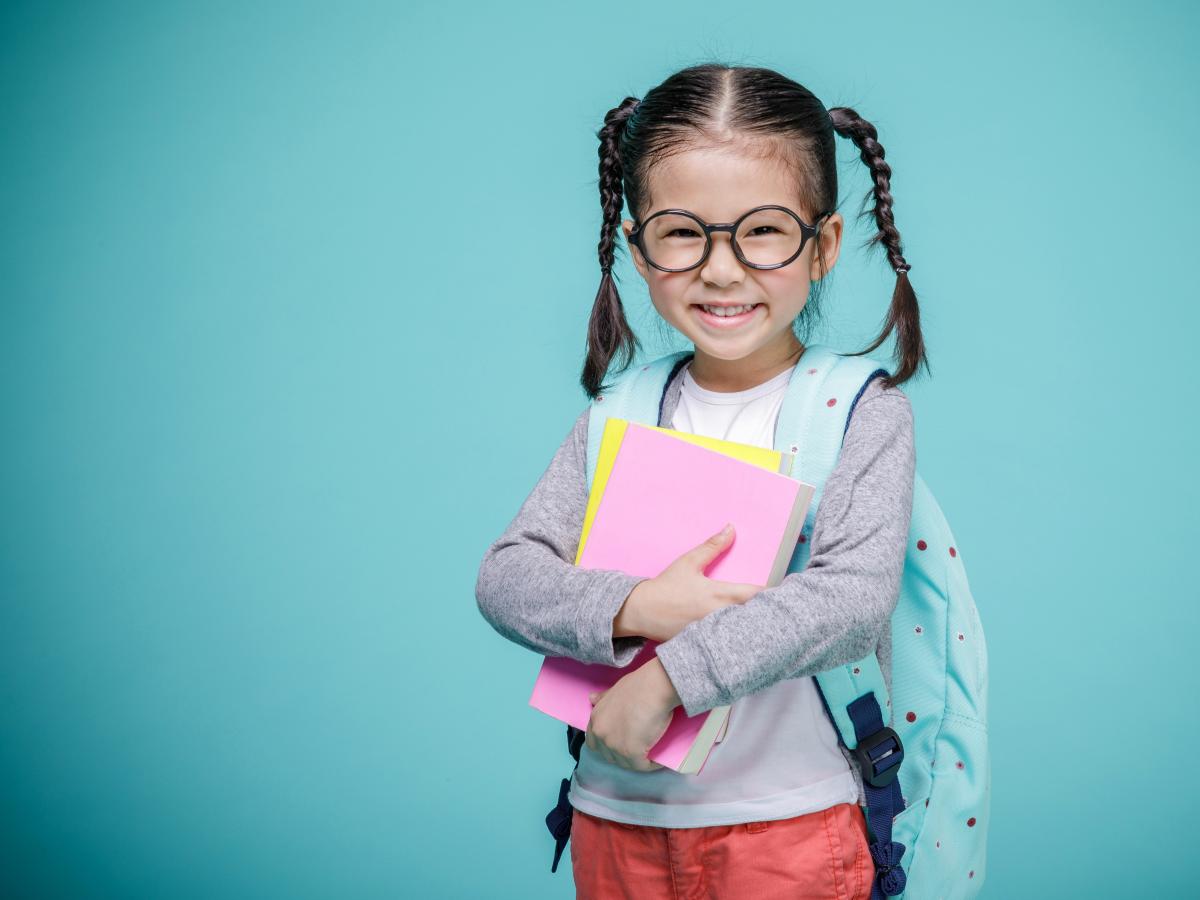 Kindergarten girl wearing a backpack and glasses. 